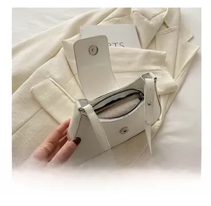 Internal view of the cream white crescent shoulder bag showing storage and zipper pocket
