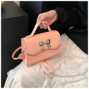 Pink textured leather handbag with a silver metal bow accent and detachable shoulder strap