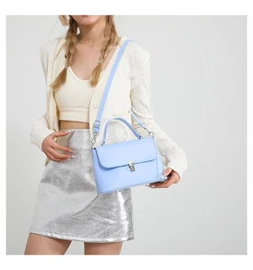 Detail of light blue PU leather bag featuring a silver metal lock and adjustable shoulder strap