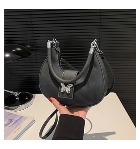 Détail du sac croissant noir avec fermoir papillon argenté et bandoulière en cuir