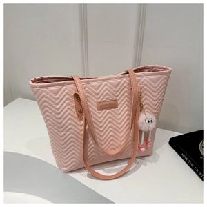 Detail of pink chevron quilted tote bag with cute plush monster charm and leather handle