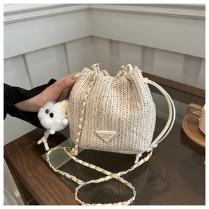 Detail of straw woven bucket bag featuring V-shaped texture and plush charm
