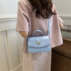 Light blue quilted crossbody bag with silver butterfly accent and V-shaped stitching