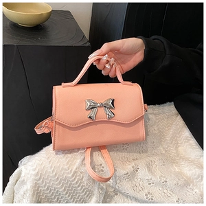 Detailed texture of pink crossbody bag featuring crosshatch leather and a silver bow buckle