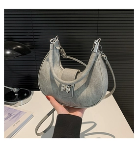 Détail du sac lune en denim gris avec boucle papillon en métal et bandoulière fine