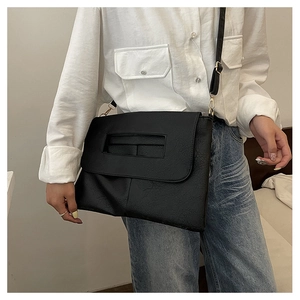 Detail of black faux leather crossbody bag with natural crack texture and gold hardware