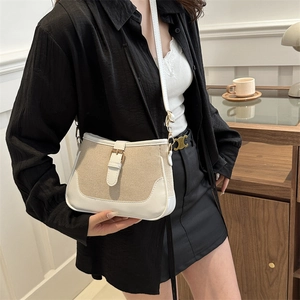 Chic beige canvas and white leather crossbody bag worn by a model in a cozy indoor setting