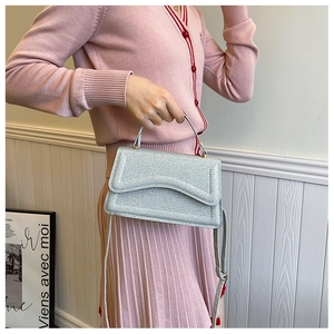 Detail of silver glitter handbag featuring a sleek flap and adjustable shoulder strap