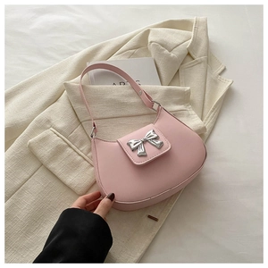 Detail of light pink leather hobo bag with silver bow buckle on beige suit jacket