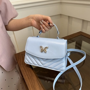 Light blue crossbody bag with gold butterfly clasp and V-quilted faux leather finish