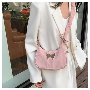 Detail of pink pleated underarm bag with silver butterfly and ruffled strap on shoulder