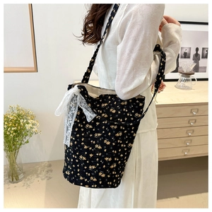 Detail of black floral bucket bag with yellow prints and white lace bow decoration