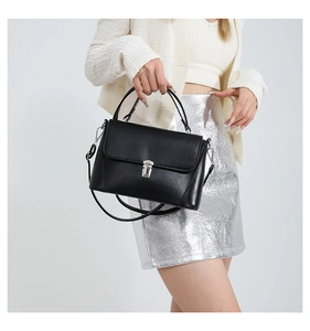 Detail of black crossbody bag with silver metal buckle and adjustable strap
