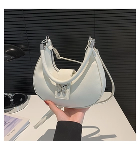 Détail du sac hobo blanc en forme de lune avec une grande boucle papillon en métal argenté