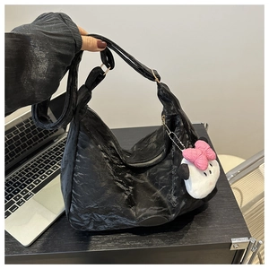 Détail du cabas plissé noir avec fermeture éclair dorée et porte-clés en peluche doux