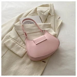 Detail of light pink saddle bag with smooth matte leather texture on a beige blazer