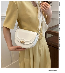 Detail of white saddle bag showing golden hardware buckle and premium leather texture