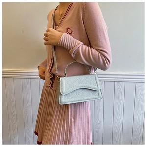 Side view of silver shimmer envelope bag with gold hardware on pink knit outfit