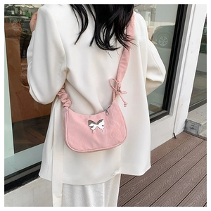 Pink crescent shoulder bag with butterfly metal detail and ruched strap on model