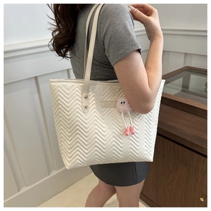 White quilted tote bag with V-stitch pattern and pink plush monster charm on shoulder