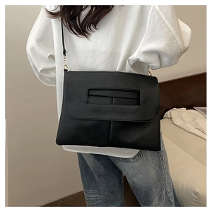 Detail of minimalist black PU leather envelope bag with gold hardware and flap closure