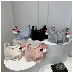 Détail de sacs seaux en nylon texturé en cinq couleurs avec pendentifs en peluche