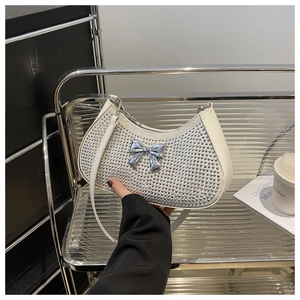 Detailed view of white half-moon underarm bag with silver rhinestones and metal bow