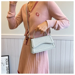 Silver glitter crossbody bag styled with a pink cardigan and pleated skirt for a chic look
