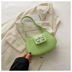 Detail of light green baguette bag featuring a large metallic silver bow on matte leather