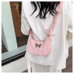 Pink shoulder bag with silver butterfly charm and pleated strap shown on a white blazer