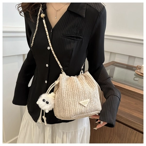 Detail of cream woven bucket bag with gold chain strap and fuzzy doll charm