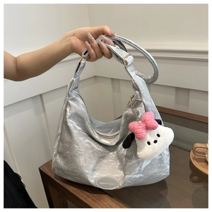 Détail d'un sac cabas argenté avec écusson logo et pendentif chien en peluche