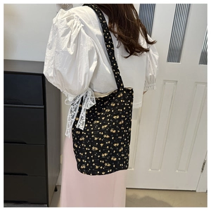 Detail of floral canvas tote bag with yellow flowers worn over the shoulder on white top