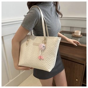 Detailed view of white quilted tote bag with V-pattern stitching and cute plush charm