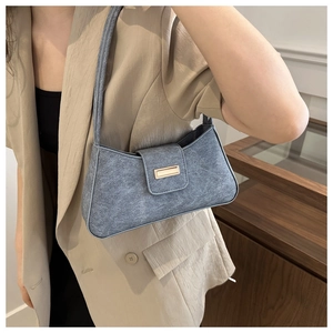 Detail of blue vintage textured baguette bag with gold rectangular metal buckle