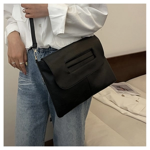 Détail du sac bandoulière noir avec texture litchi vintage et boucle métallique