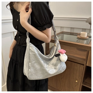 Détail du sac argenté métallisé avec texture plissée et charmant pendentif chien en peluche