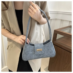 Detail of grey felt baguette bag showing the golden metal buckle and sleek texture