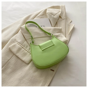 Detailed side view of grass green half-moon underarm bag with silver hardware on tweed