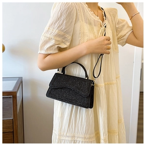 Close-up of black glitter crossbody bag with top handle and fine silver shimmer texture
