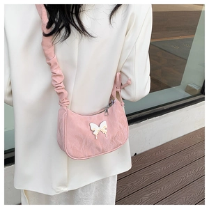 Detail of light pink ruched fabric underarm bag with decorative butterfly and cloud strap