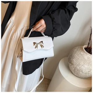 Close-up of a white textured PU square handbag with a golden butterfly metal buckle