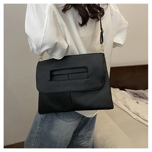 Detail of black pebbled leather handbag with cutout handle and golden metal buckle clasp