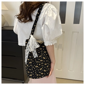 Detail of floral tote bag with white lace bow and yellow flower pattern on black canvas
