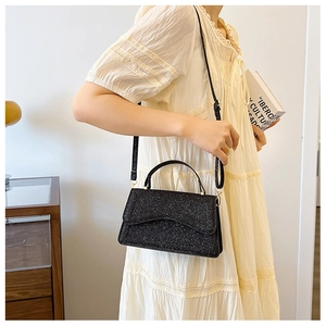 Detail of black glitter shoulder bag with wave flap design and golden metal hardware