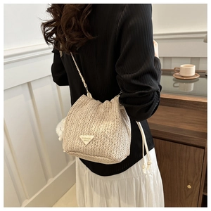Detail of woven straw bucket bag with V-shaped texture and cream triangular logo