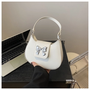 Close-up of cream crescent bag with silver bow ornament and leather texture
