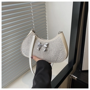 Detail of white crescent bag featuring silver studs and a 3D metallic bow buckle