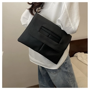 Détail de la texture cuir grainé noir et crochets dorés sur un sac bandoulière moderne