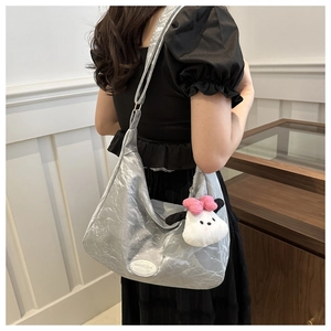 Gros plan du sac fourre-tout argenté plissé avec un joli porte-clés en peluche doux
